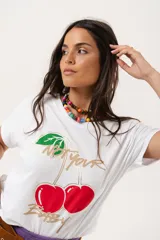 Remera blanca de algodón y elastano, con cuello redondo y mangas cortas. Estampado frontal con cerezas y texto en dorado.