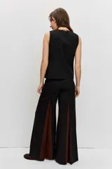 Pantalón sastrero de corte ancho y tiro alto, color negro con inserciones laterales en tono marrón que forman godets.