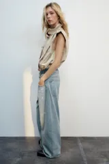 Jeans de tiro medio con cinco bolsillos, diseño holgado y efecto desgastado con detalles de rotos. Cuenta con una cintura doble combinada en contraste de tonos denim y cierre frontal con cremallera y botones metálicos.