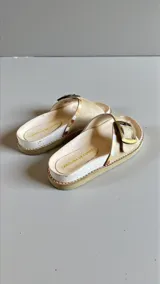 Sandalias de cuero color natural de la marca Carolina de Cunto, con capellada ancha decorada con detalles pintados a mano y una hebilla metálica lateral.