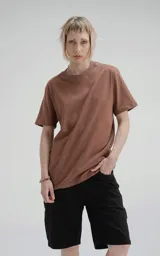 Remera de manga corta y cuello redondo, color marrón (mocca), confeccionada en algodón premium suave. Presenta un calce regular con un recorte distintivo en la espalda.