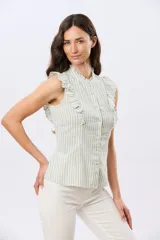 Musculosa de lino rayada con cuello mao y volados en los hombros. Presenta diseño de rayas verticales y aplique de etiqueta con logo en la parte posterior.
