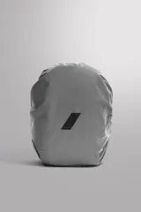 Funda de mochila gris confeccionada en tejido técnico, ajustable al tamaño de la mochila. Tiene dos ganchos para sujetar a la mochila y detalle de logo estampado. Es plegable tamaño bolsillo.