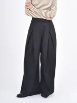 Pantalón de vestir negro de corte wide leg, con pinzas frontales y cintura alta.