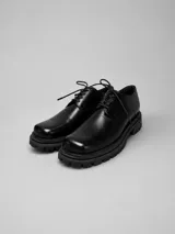 Zapato de cuero negro con cordones y suela chunky de goma con plataforma estriada.
