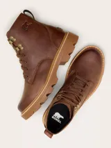 Bota de caña media Sorel, confeccionada en cuero impermeable color marrón tabaco. Presenta cierre con cordones, detalles metálicos en los ojales, logo de la marca grabado en el lateral y suela de caucho dentada en tono contrastante.