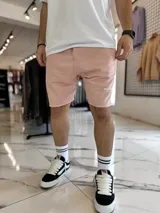 Bermuda de jogging color beige, con bolsillos laterales y estampa con texto blanco en la pierna izquierda.