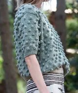 Sweater marrón de manga corta confeccionado en 100% lana merino con textura de bodoques tridimensionales en relieve y cuello redondo a la base.