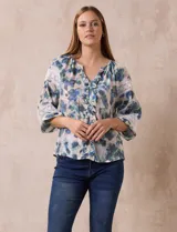 Blusa estampada con flores azules y verdes, cuello a la base con escote en V y volados. Manga larga con puño y apliques de puntilla.