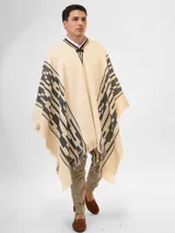 Poncho color crema con diseño geométrico en negro y marrón, con cuello en V y flecos en el borde inferior.