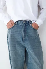 Jean de corte baggy con silueta holgada y relajada, confeccionado en denim de algodón con lavado azul clásico. Presenta diseño de cinco bolsillos, cintura con trabillas y cierre frontal con botón y cremallera.