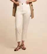 Pantalón de sastrería estilo carrot color blanco, de tiro alto, con trabillas en la cintura y cierre frontal de cremallera y botón.