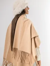 Ruana gris de tejido de punto con flecos en el ruedo.