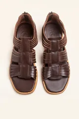 Sandalia de cuero color marrón chocolate, con suela plana y diseño calado con detalles trenzados.