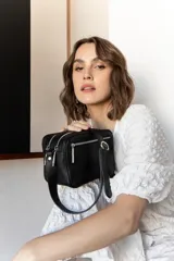 Bandolera rectangular de cuero color nude, con correa larga ajustable y doble cierre superior con cremallera metálica plateada.
