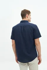 Camisa de manga corta confeccionada en una mezcla de lino y algodón, con cuello clásico, cierre frontal de botones y bolsillo en el pecho con logo bordado.