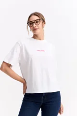 Remera de algodón color verde oliva, con corte relajado y manga corta. Presenta una estampa gráfica grande en la espalda con motivos florales abstractos y texto.