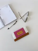 Billetera de cuero con estampado reptil en color marrón y fucsia con detalles en blanco. Tiene un sistema de cierre con broche y monedero externo.