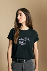 Remera negra de manga corta con puños doblados y la frase "la dolce vita" bordada en blanco en el frente.