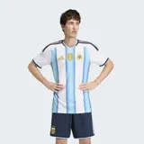 Camiseta de fútbol Adidas de la Selección Argentina, modelo titular 2026, versión jugador. Diseño a rayas verticales celestes y blancas, con cuello redondo y detalles en azul marino en las mangas y hombros. Incluye escudo de la AFA y logo de Adidas en dorado, además del parche de campeón FIFA.