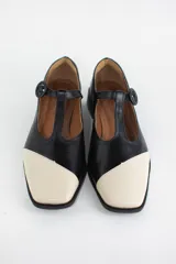 Zapatos estilo Mary Jane de cuero con acabado acharolado y textura efecto croco en color marrón oscuro. Presentan punta cuadrada, cierre con tira en el empeine y taco cuadrado bajo.