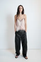 Pantalón cargo de tiro alto confeccionado en material efecto piel. Presenta bolsillos laterales con solapa, bolsillos delanteros y traseros, con cierre frontal de cremallera y gancho metálico.