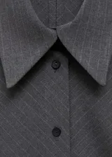 Vestido corto de estilo camisero con diseño cruzado, cuello clásico y cierre frontal de botones. Presenta mangas largas con puños abotonados y un sutil estampado de raya diplomática.
