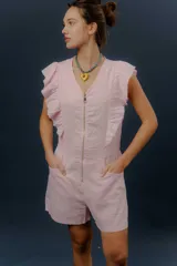 Mono corto de lino color beige, con cierre frontal, bolsillos laterales y detalles de volados en los hombros.