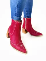 Botas texanas de cuero rojo, con taco cuadrado de madera, puntera fina y detalles de costuras blancas en contraste con diseño en la puntera y el lateral. Cuenta con cierre lateral y elástico interno.