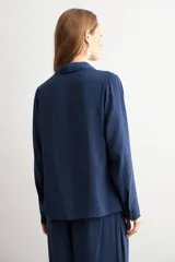 Camisa de corte clásico y calce holgado, con cuello camisero, cierre frontal de botones y mangas largas con puños abotonados.