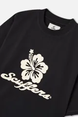Remera de algodón color negro con corte boxy y cuello redondo acanalado. Presenta un estampado frontal con una flor de hibisco y el logotipo de la marca en tipografía cursiva, además de un pequeño logo impreso en la parte posterior.