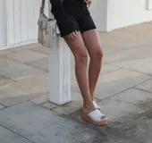 Zuecos de cuero con plataforma de madera, diseño croco color blanco y tachas doradas.