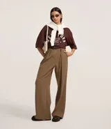 Pantalón de vestir ancho (pantalona) color marrón, con pliegues frontales, cintura alta con cinturón y cierre tradicional.