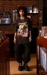 Remera de manga corta con cuello redondo y calce oversize, color negro con efecto nevado. Presenta un estampado gráfico frontal con el logo de la banda The Prodigy y elementos artísticos.