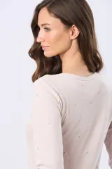 Remera de algodón color beige con sutil estampado floral en tonos pastel, escote redondo y manga larga.