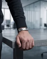 Pulsera de diseño moderno compuesta por una banda central de acero inoxidable con acabado cepillado y detalles en relieve, combinada con una correa de goma negra ajustable.