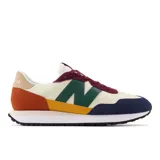 Championes New Balance modelo MS237VE, con capellada de nylon color crema, superposiciones de gamuza en azul marino, verde, amarillo, naranja y bordó. Logo "N" en verde y suela de goma color caramelo.