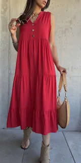 Vestido midi rojo sin mangas con botones decorativos en el escote y corte escalonado.