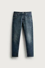 Jeans skinny fit de hombre en color azul oscuro con efecto lavado y roturas sutiles. Presenta diseño de cinco bolsillos, trabillas para cinturón y cierre frontal con botón y cremallera.