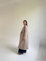 Tapado largo de paño en color beige, con solapas anchas, cierre frontal de un botón y diseño estructurado.