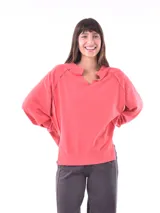 Buzo color salmón, de corte holgado y cuello con abertura en forma de V.