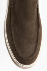 Mocasines de gamuza color marrón con acabado cepillado, costura tradicional en el empeine y suela de goma blanca.