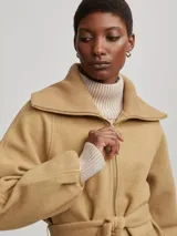 Tapado color camel con cierre frontal y lazo para ajustar en la cintura. Tiene cuello alto y mangas largas con volumen.