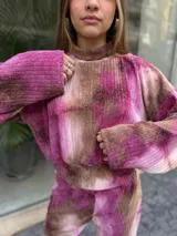 Conjunto de dos piezas compuesto por un buzo corto de manga larga y un pantalón de pierna ancha, confeccionado en tela morley elastizada con estampado tie-dye en tonos fucsia y marrón.