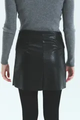 Falda corta de ecocuero con textura tipo croco, diseño cruzado con cierre metálico frontal y tajo lateral.
