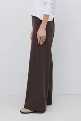 Pantalon de corte sastrero y pierna ancha, confeccionado en tela melange. Presenta cintura con trabillas, cierre frontal con botón y bolsillos laterales.