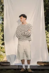 Sweater de tejido ligero a rayas horizontales blancas y negras, con cuello redondo y mangas largas. Presenta un pequeño bordado en la manga.