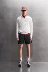 Pantalones cortos deportivos color marrón rojizo, confeccionados en tejido técnico ligero y elástico. Presentan cintura elástica ajustable con cordón interior, bolsillos frontales y un bolsillo trasero con cierre de cremallera. Los laterales tienen perforaciones para transpirabilidad y aberturas laterales en el bajo.