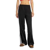 Pantalón deportivo Adidas de la línea Originals, confeccionado en tejido tricot de poliéster reciclado. Presenta un corte holgado con cintura media elástica, bolsillos laterales con cierre y el icónico diseño de las tres tiras blancas a lo largo de las piernas.