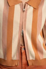 Cárdigan tejido con cierre frontal, diseño a rayas horizontales en tonos naranja, beige y rosa, cuello tipo polo y mangas abullonadas.